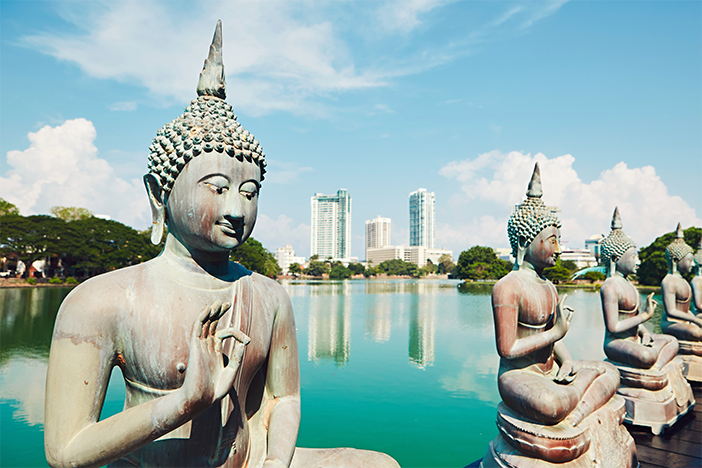 Statues by a tranquil lake at Gangaramaya Temple, Colombo